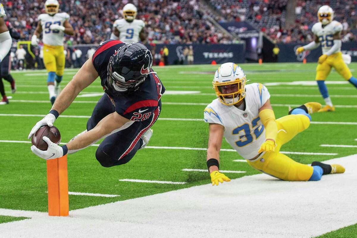 Houston Texans running back Rex Burkhead (28) stretches the ball across the goal line as hew runs past Los Angeles Chargers safety Alohi Gilman (32) for a 25-yard touchdown run during the first quarter of an NFL football game Sunday, Dec. 26, 2021 in Houston.