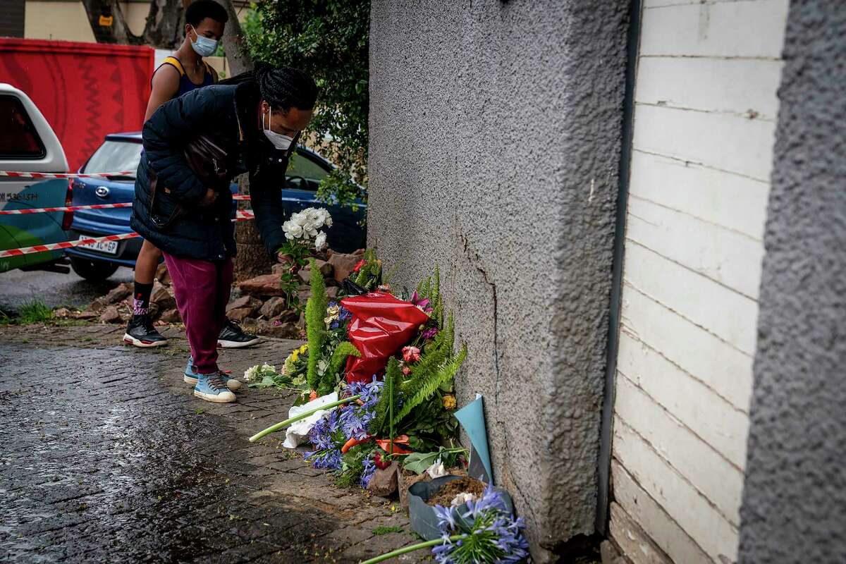 A woman places flowers outside the historical home of Anglican Archbishop Desmond Tutu, in Soweto, Johannesburg, South Africa, Monday, Dec. 27, 2021. South Africa's president says Tutu, South Africa's Nobel Peace Prize-winning activist for racial justice and LGBT rights and the retired Anglican Archbishop of Cape Town, died Sunday at the age of 90.