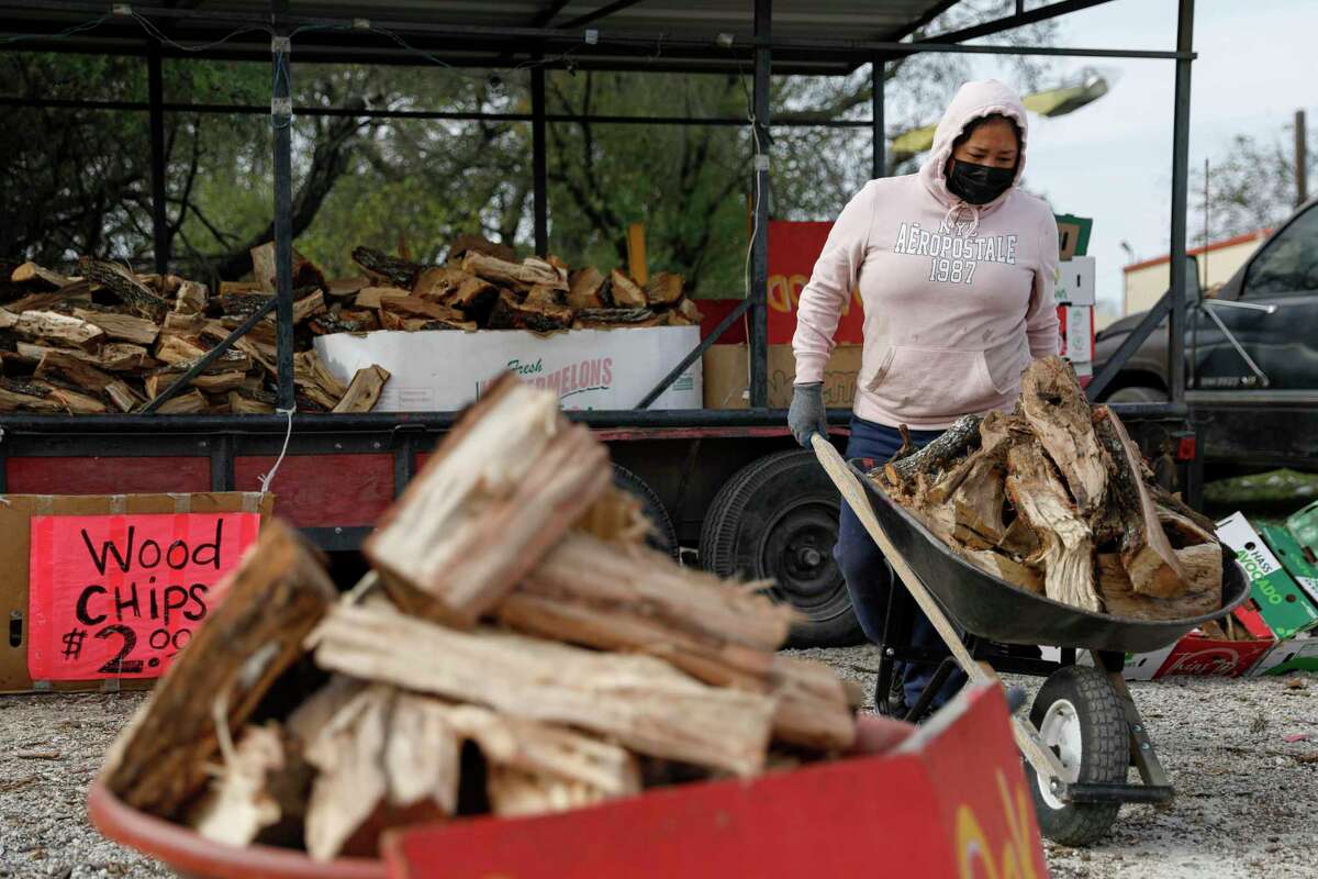 Alyssa Villarreal prepares to offload a wheelbarrow of wood to a customer at her street vending stand near the corner of East Ashley Road and Roosevelt Avenue on the South Side on Dec. 11, 2021. She currently charges $25 for a wheelbarrow of wood; prices vary with the seasons.