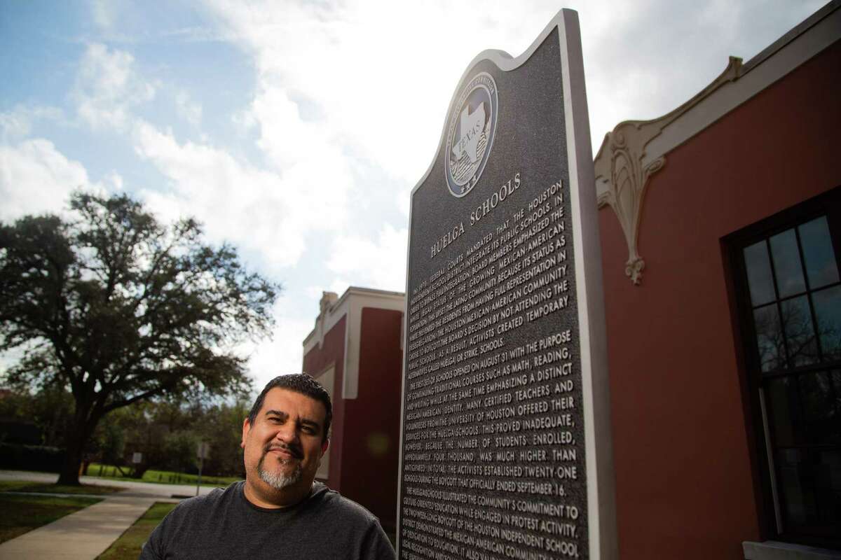 Texas 2022 Poet Laureate Lupe Mendez stands in front of a Huelga Schools historic marker at the Leonel Castillo Community Center on Tuesday, December 14, 2021, in Houston.  Huelga Schools were schools established in Houston so that Mexican-American students who were part of the strikes could continue their education in the 1970s. The strikes were directed against the Houston Independent School District (HISD).
