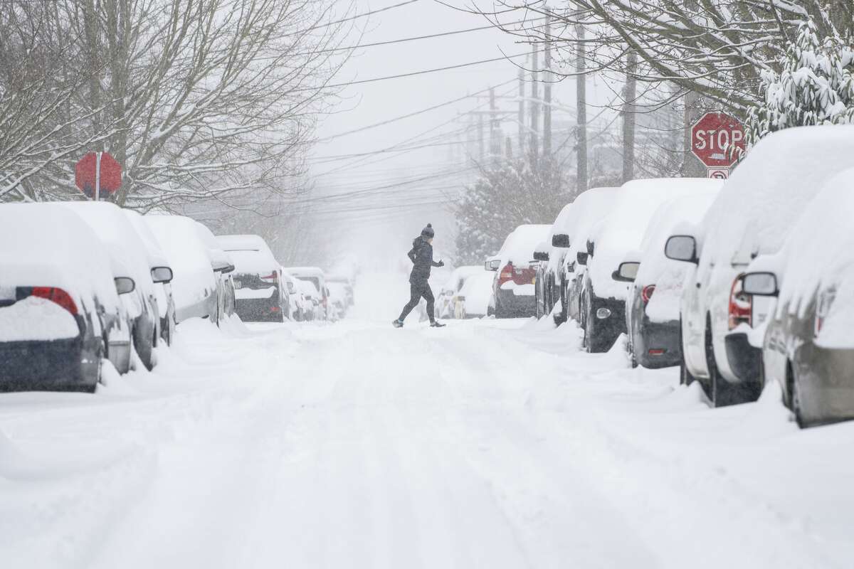 SEATTLE, WA - FEBRUARY 13: A jogger makes their way across a snowy street on February 13, 2021 in Seattle, Washington. A large winter storm dropped heavy snow across the region. (Photo by David Ryder/Getty Images)