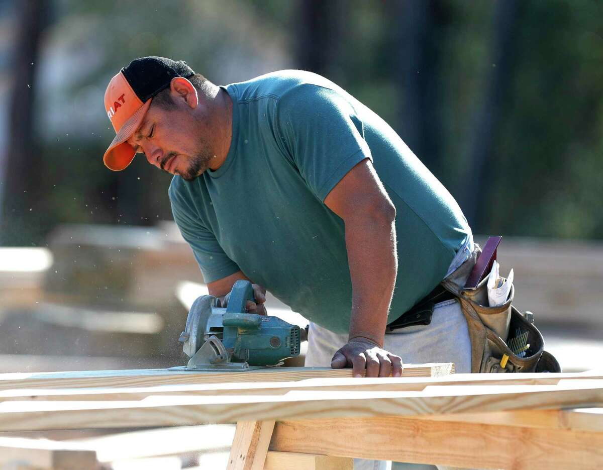 A man cuts wood for framing for a home in The Woodlands Hills master planned community, Thursday, Dec. 23, 2021, in Willis.