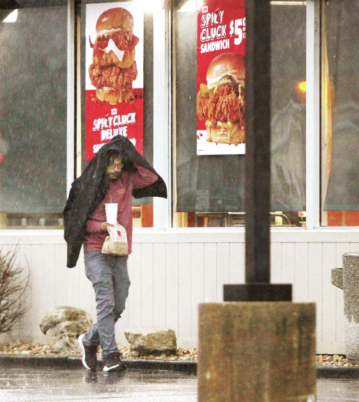 John Badman|The Telegraph A man uses his coat for an umbrella Tuesday as he leaves the Wood River Jack in the Box restaurant on Edwardsville Road. 