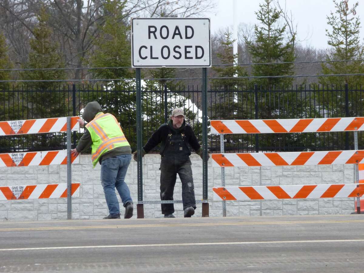 Workers remove road closure signs at the M-55 bridge in Manistee Township. After some delays, the bridge reopened to motorists on Dec. 28. 