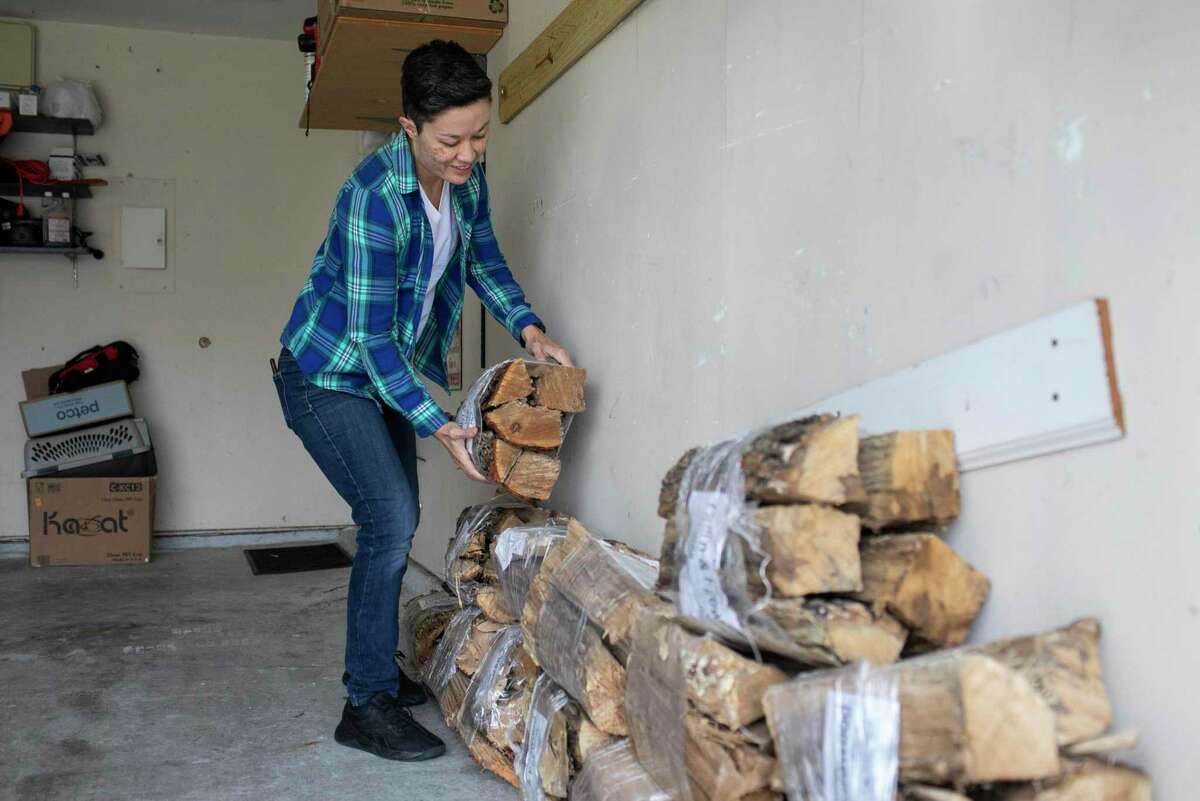 K.P. Power stacks bundles of wood in their garage in San Antonio on Dec. 11. Power and her wife have been stocking up to prepare for winter even more this year after having experienced the intense winter storm that swept through Texas in February.