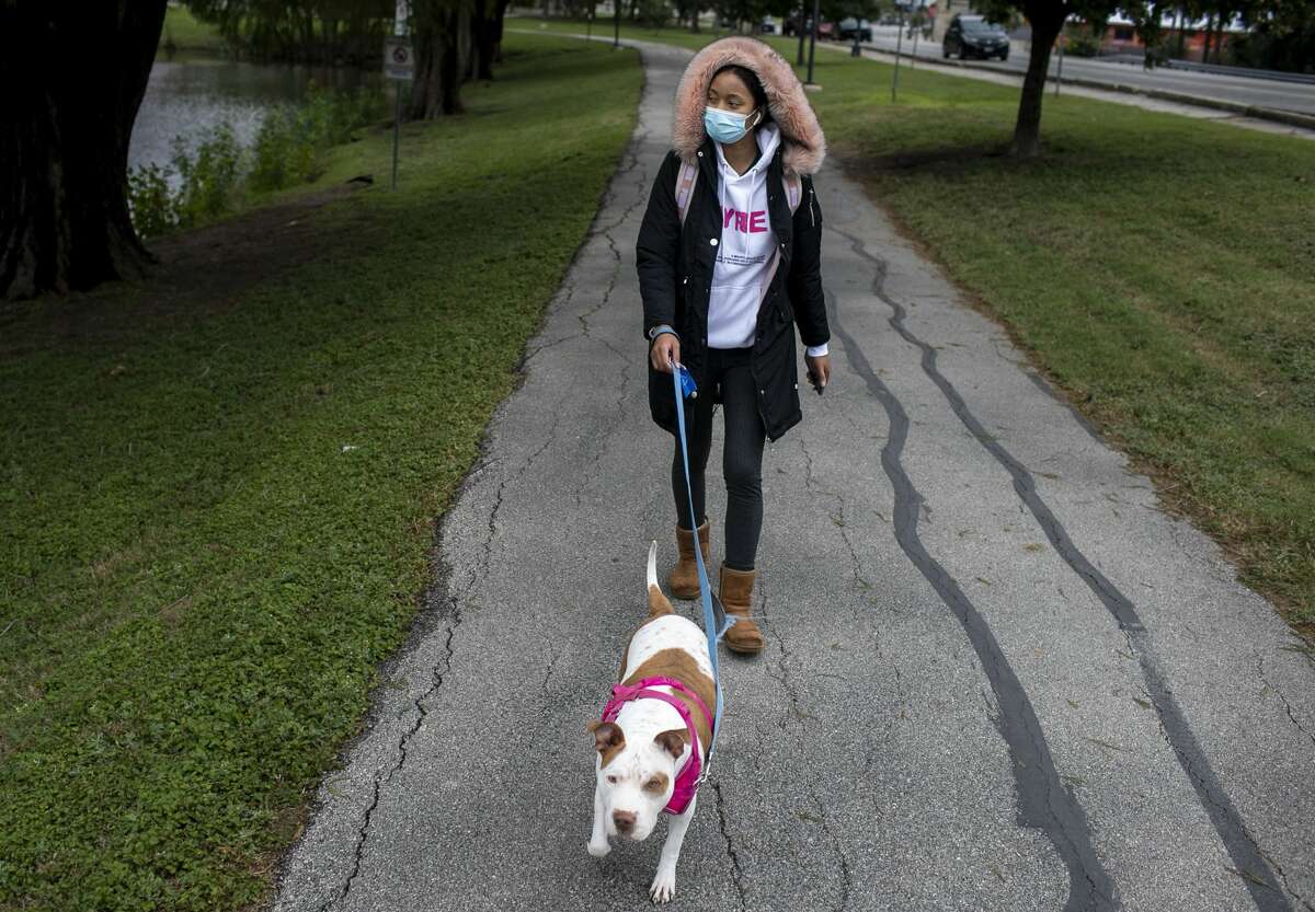 Courtney walks her dog Maezie, who she fostered and then ended up adopting during the pandemic, at Woodlawn Lake Park in San Antonio.