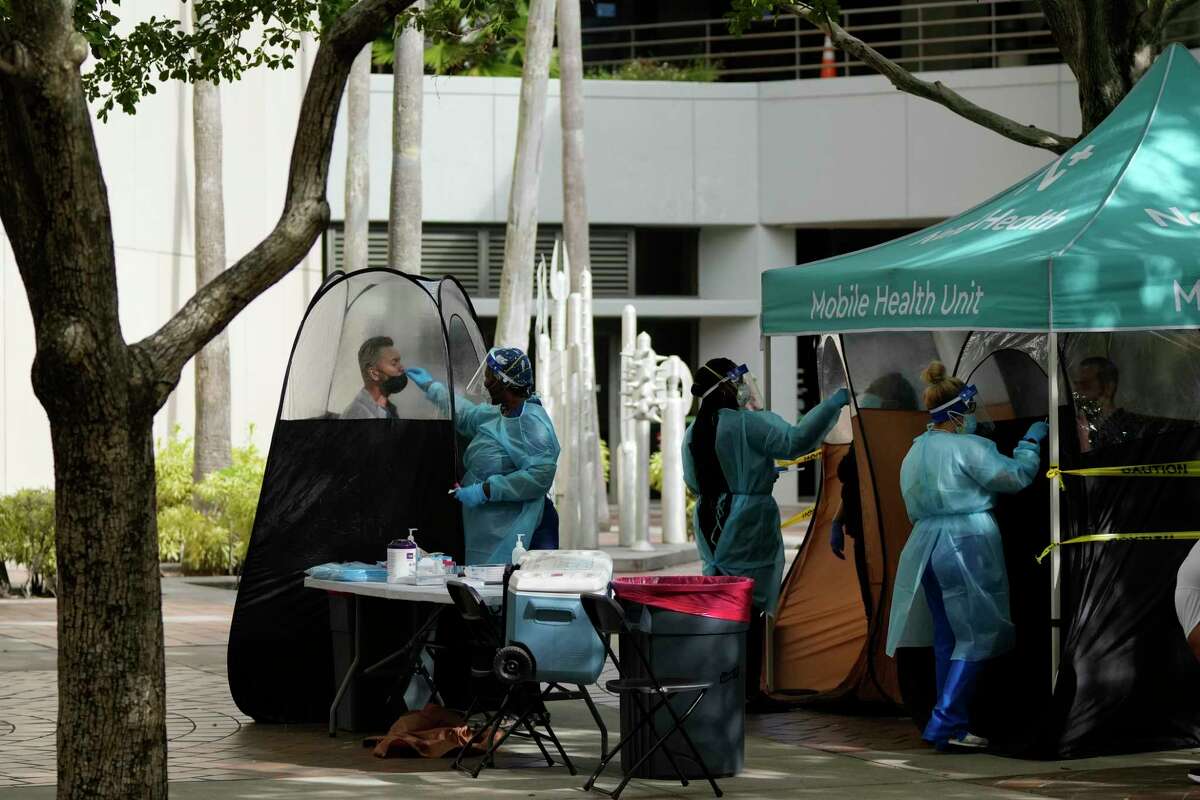 FILE - People are tested for COVID-19, at a walk-up testing site run by Nomi Health, Tuesday, Dec. 28, 2021, in downtown Miami. More than a year after the vaccine was rolled out, new cases of COVID-19 in the U.S. have soared to the highest level on record at over 265,000 per day on average, a surge driven largely by the highly contagious omicron variant.