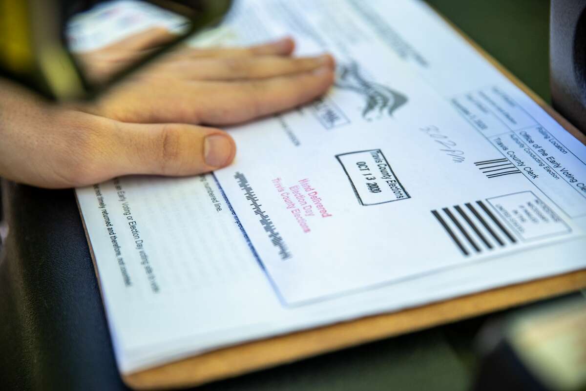 A poll worker stamps a voters ballot before dropping it into a secure box at a ballot drop off location on October 13, 2020 in Austin, Texas.