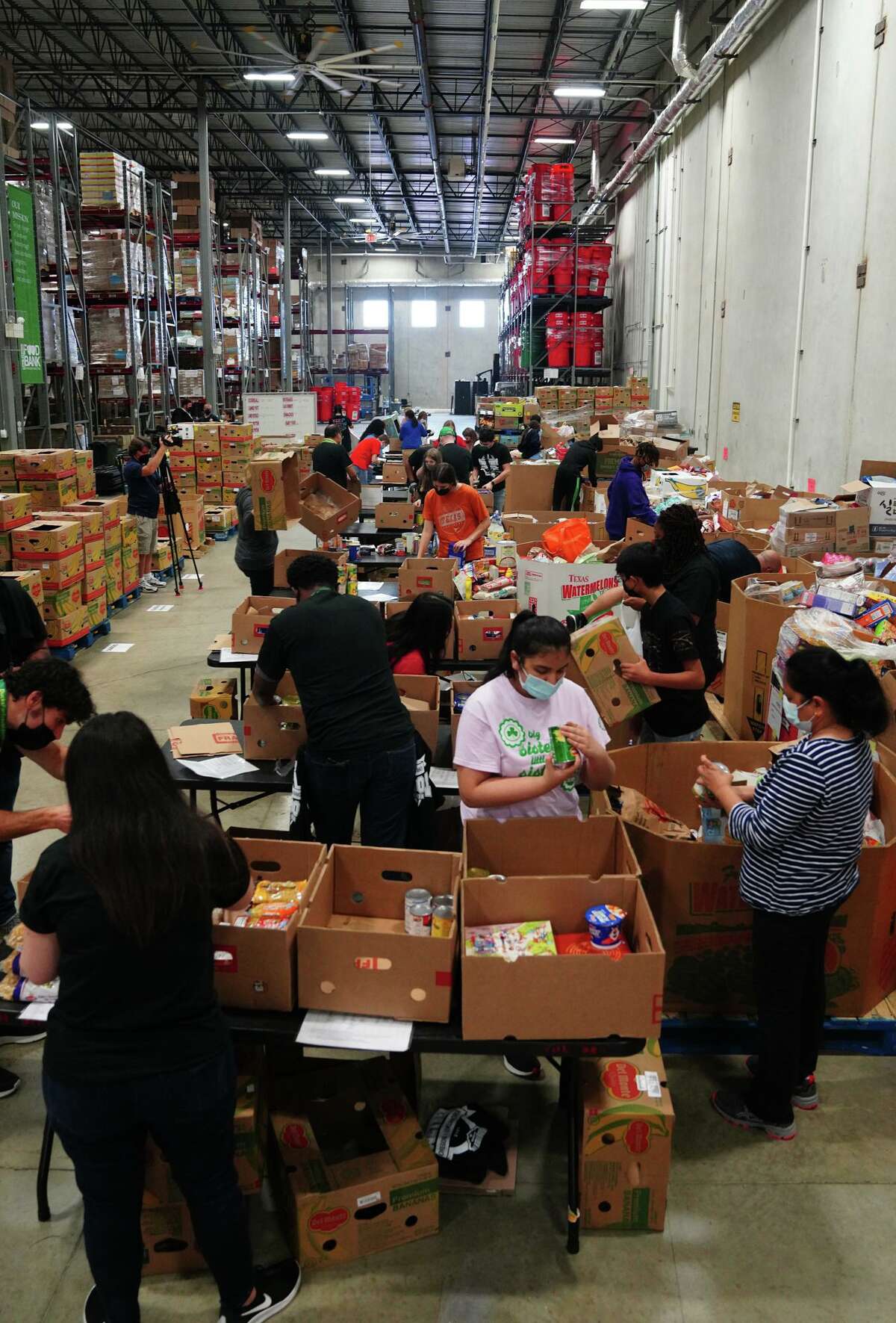 People sort items during a volunteer event Wednesday at the San Antonio Food Bank prior to the Alamo Bowl between Oklahoma and Oregon.