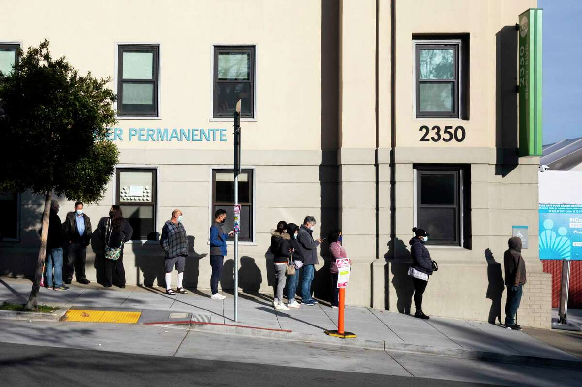 People line up hoping to receive a COVID-19 booster shot at Kaiser Permanente on Geary Boulevard in San Francisco before Christmas.