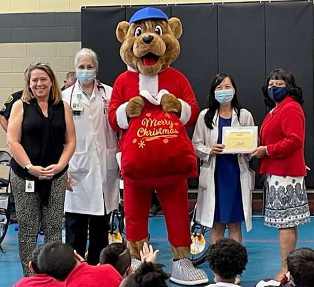 Kelsey Bear prepares to give teddy bears to Horn Elementary School students as part of the Houston Police Blue Santa Program benefiting children in underprivileged communities. From left are Mary Starling, principal, Horn Elementary School; Marina Ramirez, M.D., pediatrician, Kelsey-Seybold Clinic; Kelsey Bear; Jennifer Lai, M.D., pediatrician, Kelsey-Seybold Clinic; and Dee Jones, business and community coordinator, Alief ISD.