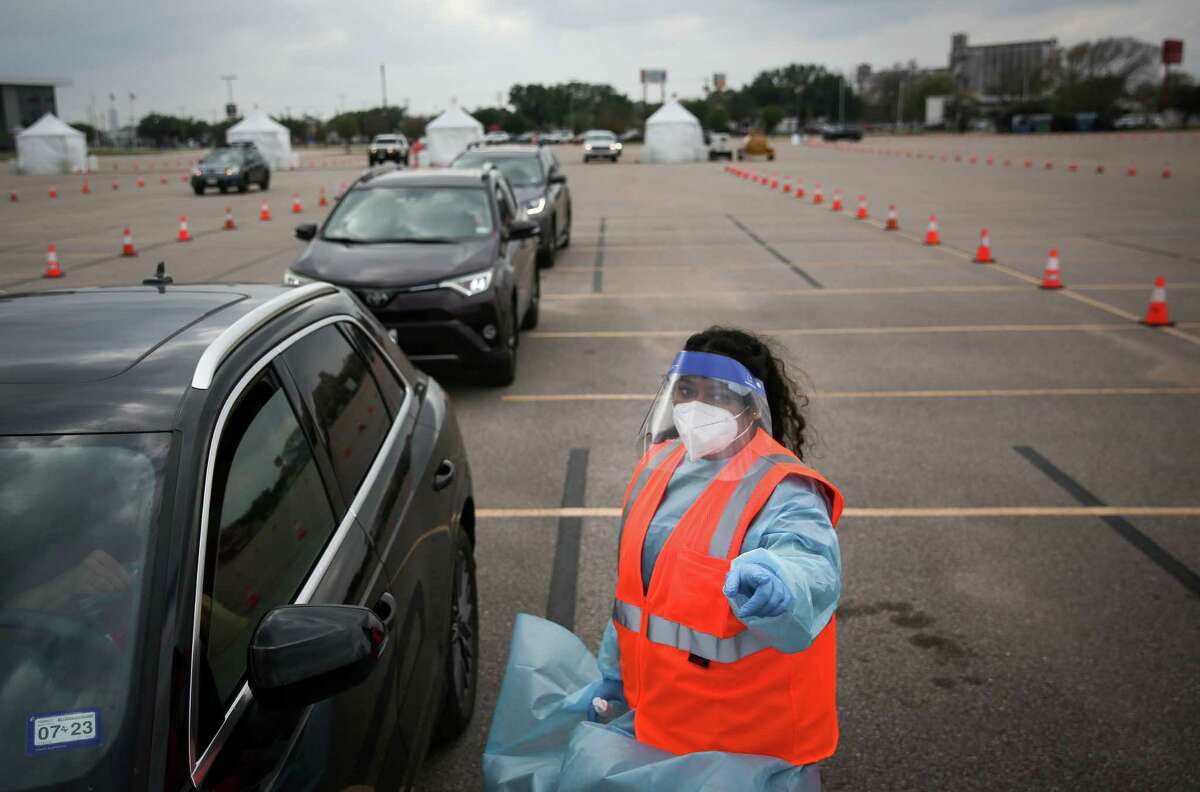 Claudia Hernandez helps a person take a COVID-19 test Wednesday at Delmar Stadium in Houston, a drive-thru mega site that opened that morning.