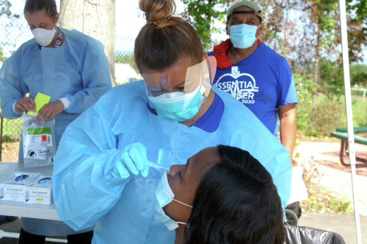 Carmen Rivera Torres, a nurse from Southwest Community Health Center, administers at COVID-19 test to Tia Reid, of Bridgeport, during a free community Coronavirus test screening event at Liberation Programs, in Bridgeport, Conn. July 9, 2020.