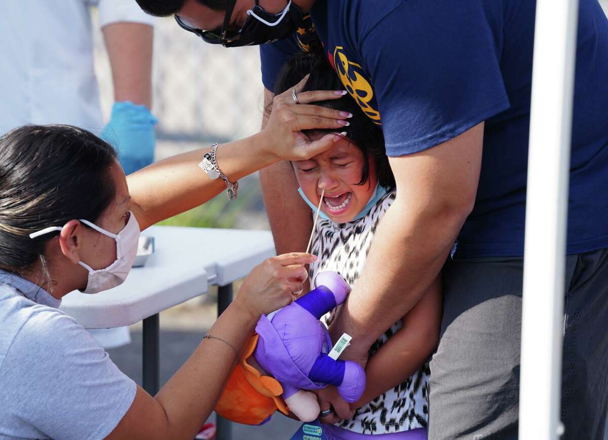 Anissa Robles cries while her mother, Daniella Robles, administers a COVID-19 test at a testing site on Fredericksburg Road as her father, Joseph Robles, tries to comfort her. Officials expected over 400 people Wednesday and were booked solid through Friday as appointments were mandatory.