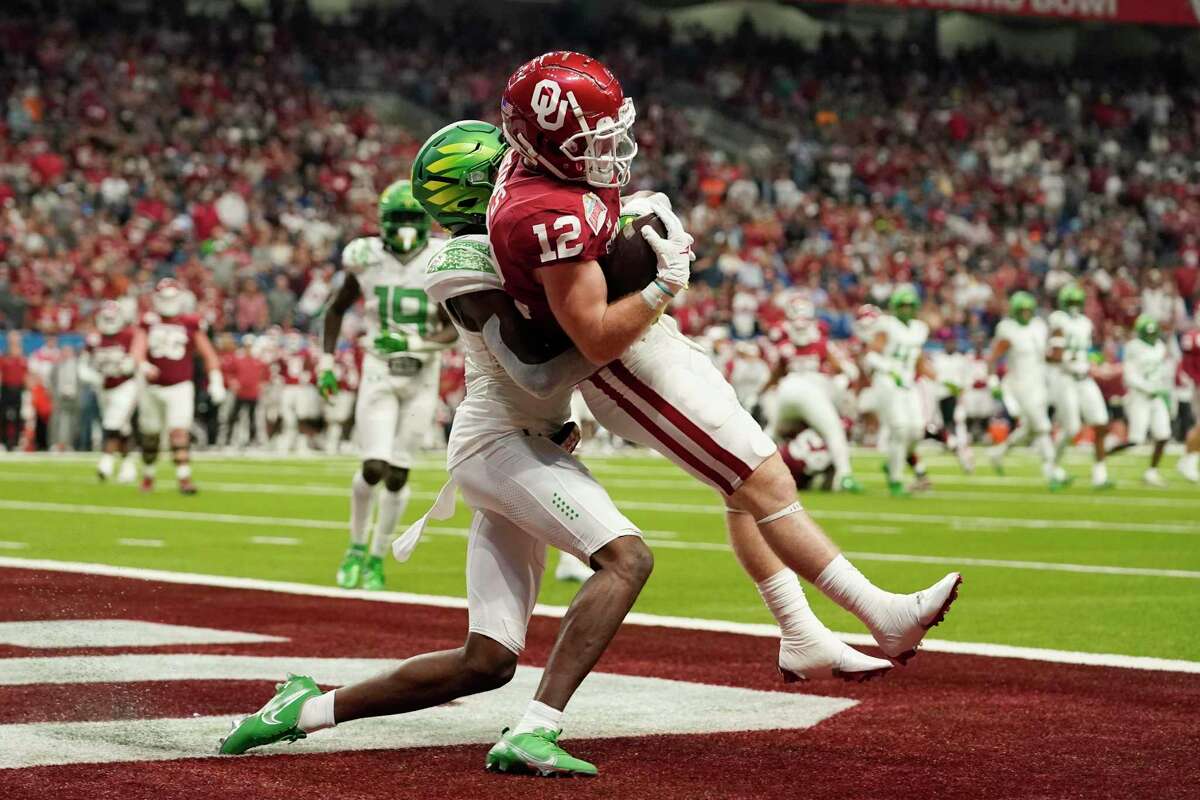Oklahoma wide receiver Drake Stoops (12) makes a touchdown catch over Oregon cornerback Trikweze Bridges (11) during the first half of the Alamo Bowl NCAA college football game, Wednesday, Dec. 29, 2021, in San Antonio. (AP Photo/Eric Gay)