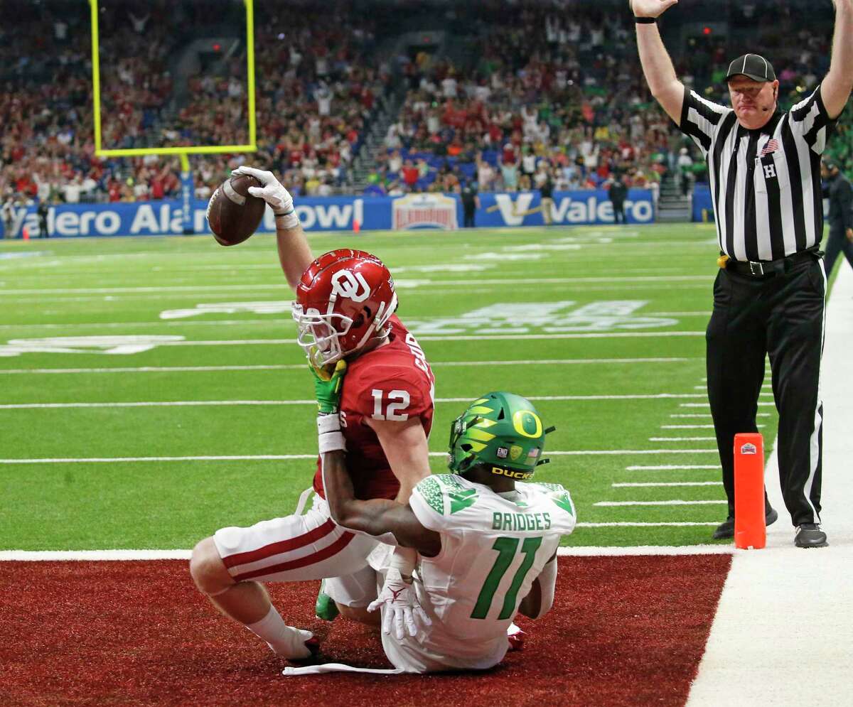 SAN ANTONIO, TX - DECEMBER 29: Drake Stoops #12 of the Oklahoma Sooners scores on a touchdown reception as Troy Franklin #11 of the Oregon Ducks defends in Valero Alamo Bowl at the Alamodome on December 29, 2021 in San Antonio, Texas. (Photo by Ronald Cortes/Getty Images)