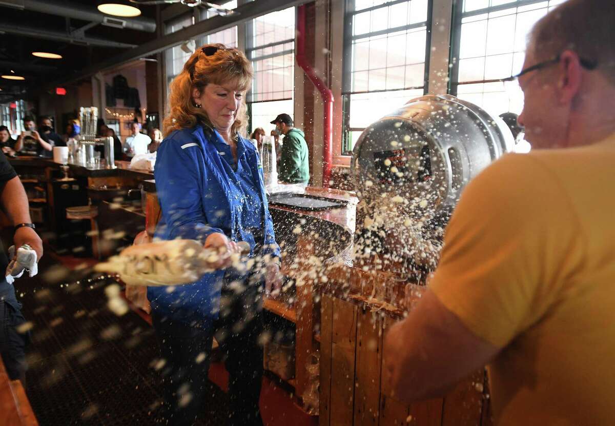 Beer flies thru the air as Stratford Mayor Laura Hoydick taps a keg of Herzzoner, the company's seasonal Maibock beer, with the help of company founder and CEO Brad Hittle at Two Roads Brewing Company in Stratford, Conn. on Thursday, May 6, 2021.