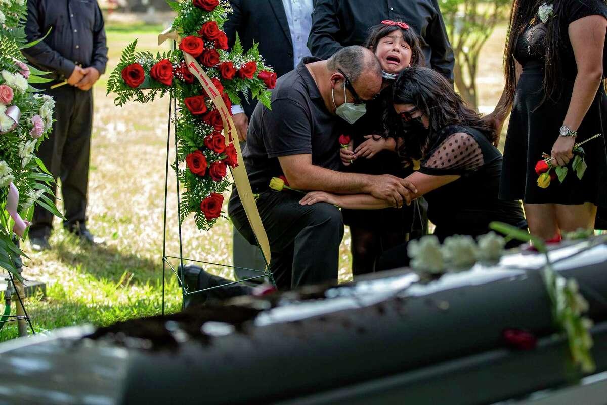 Sergio Gonzalez and daughters Sophia and Destiny embrace near the coffin of wife and mother Veronica Bustos Gonzalez. On Friday, family and friends gathered at Mission Park Funeral Chapels South to bury Veronica, her sister and her father, who died from COVID-19 within eight days of each other in August.