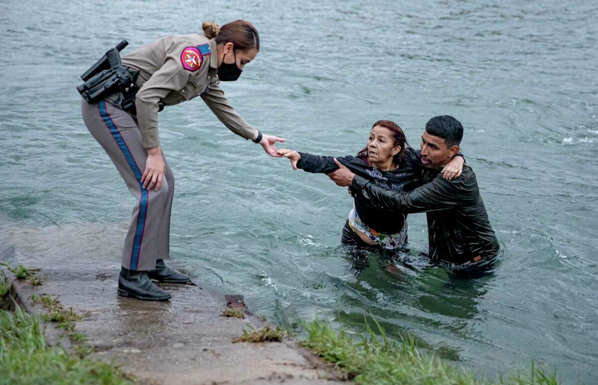 A smuggler carries Venezuelan migrant Belkis Salas across the Rio Grande near Del Rio on Friday, April 30, 2021. Salas fell at the halfway point of the river crossing. A DPS agent helps Belkis out of the river and onto American soil.