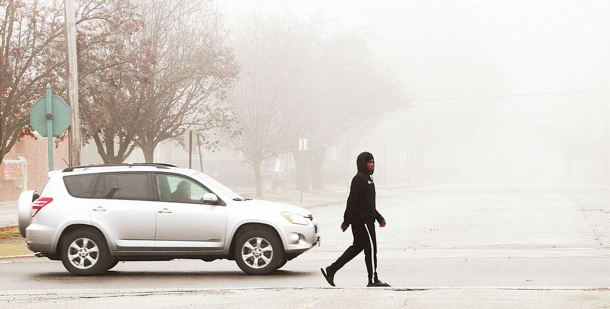 John Badman|The Telegraph A man goes for what looked like a lonely walk Thursday through the fog on Washington Avenue at Edwards Street in Upper Alton. Friday temperatures are forecast to reach 64 degrees before colder weather arrives this weekend.