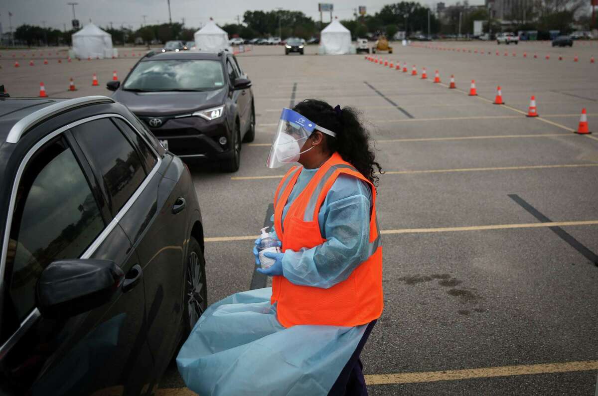 Claudia Hernandez helps a person take a COVID-19 test Wednesday, Dec. 29, 2021, at Delmar Stadium in Houston. The Houston Health Department and Curative opened the drive-thru mega-site that morning.