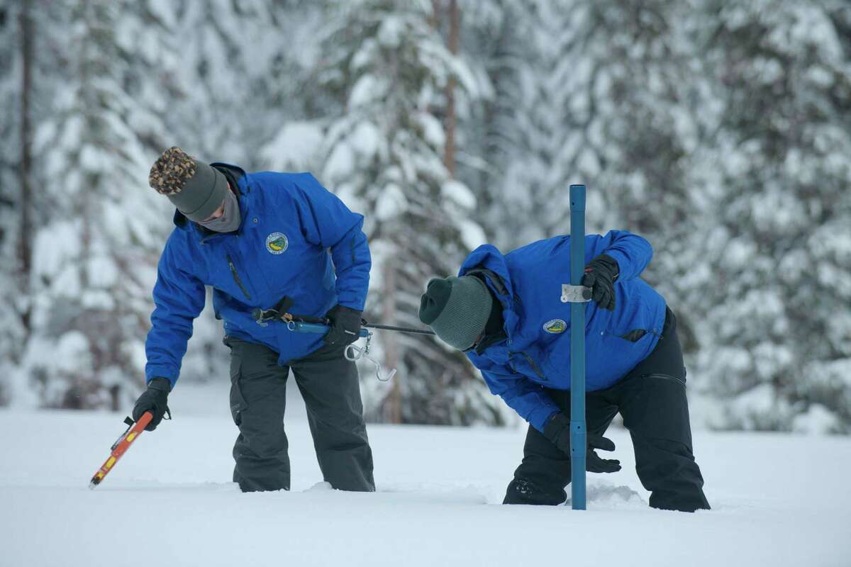 Anthony Burdock, left, and Sean de Guzman, chief of snow surveys for the California Department of Water Resources, check the depth of the snow pack during the first snow survey of the season at Phillips Station near Echo Summit, Calif. on Dec. 30, 2021. The survey found the snowpack at 78.5 inches deep with a water content of 20 inches. Statewide, the snow holds 160% of the water it normally does this time of year.