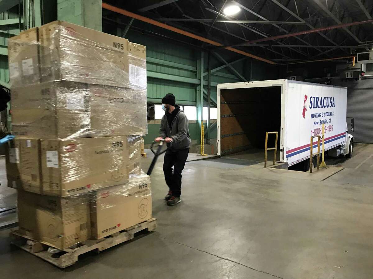 Tim O’Connor, an employee of Siracusa Moving and Storage, loads boxes of N95 masks onto a truck in the New Britain warehouse used by the state of Connecticut. The masks are part of the shipment of 6 million going to cities and towns.
