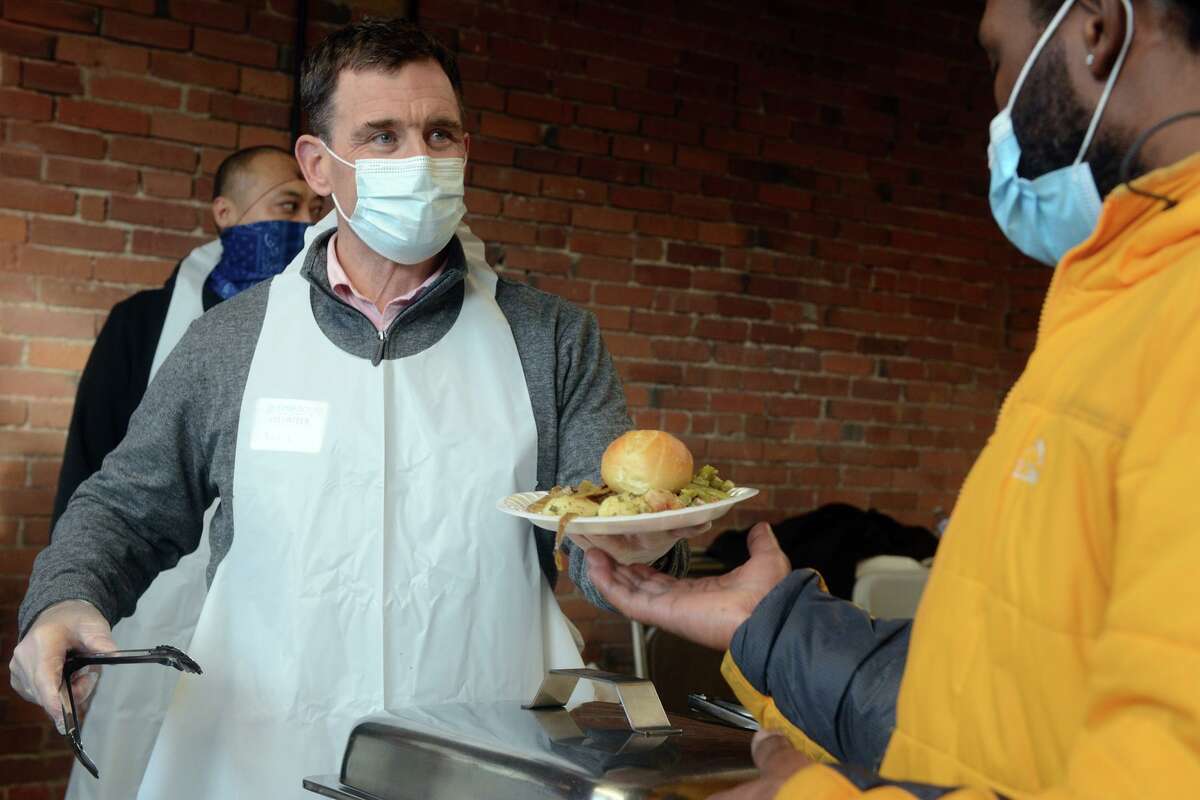 Staff member Nick Lieder serves food during the holiday meal at Open Doors, in Norwalk, Conn. Dec. 23, 2021.