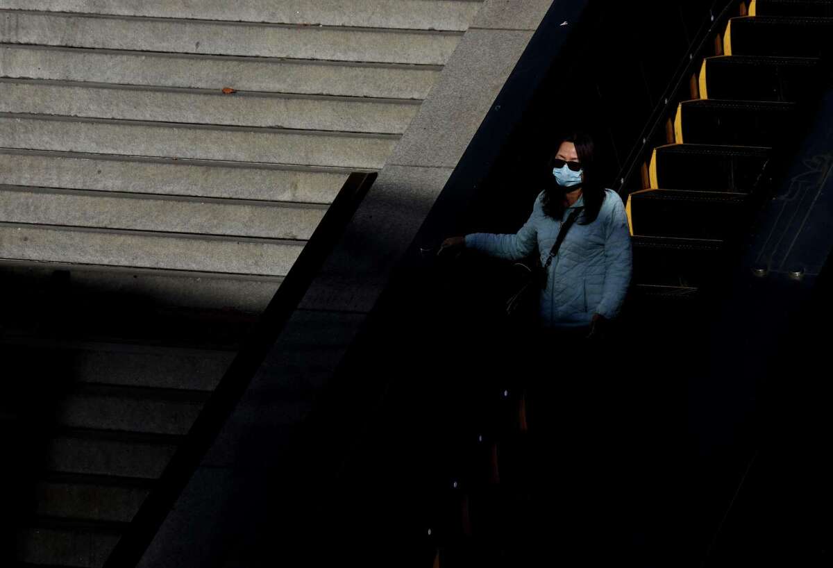 骑着电动扶梯的女人当她准备抓住巴特上个月在鲍威尔街站。城市本周宣布,其面具授权将延至2月15日。