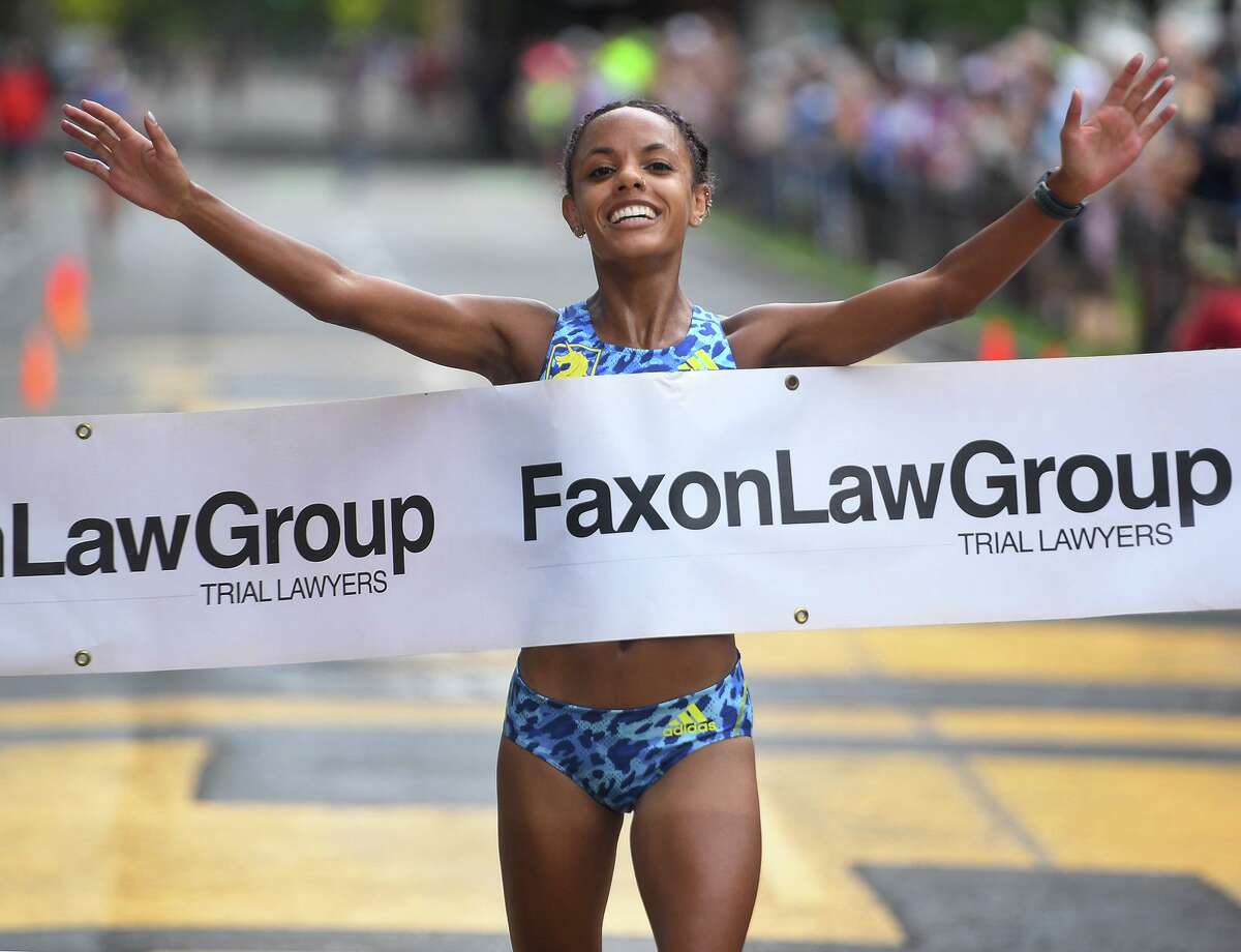 Erika Kemp, of Brookline, MA, smiles and raises her arms in victory as she wins the New Haven Road Race national championship 20k in New Haven, Conn. on Monday, September 6, 2021.