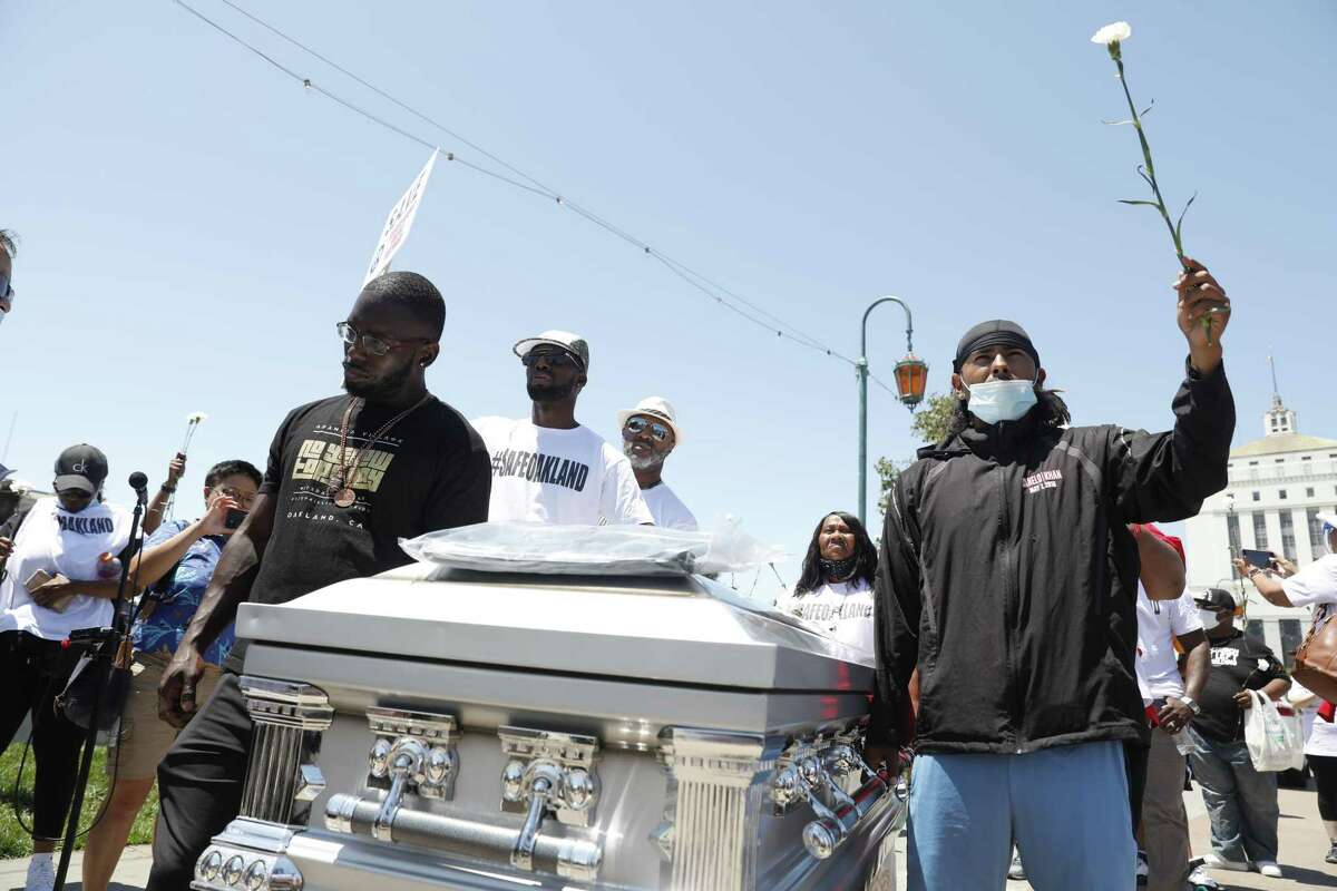 Adamika Village members move a symbolic coffin during a rally called “STAND UP FOR A SAFE OAKLAND” hosted by the Oakland Police Department in Oakland, Calif., on Saturday, July 10, 2021. The coffin represents those who have been victims of gun violence in Oakland this year.