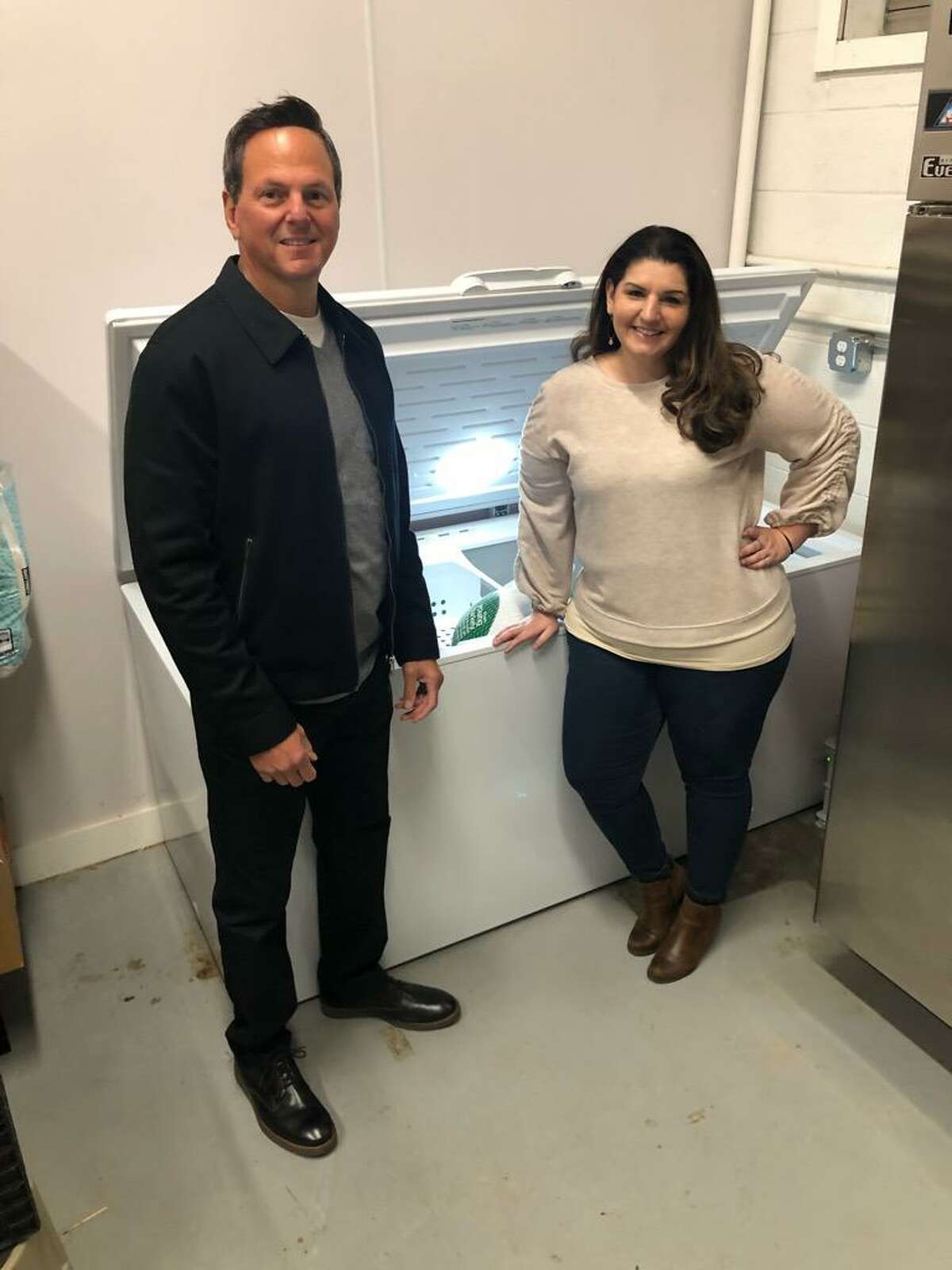 Community Dining Room Executive Director Judy Baron, right, poses with a chest freezer donated by Hallock's in Branford and Michael Vizziello, left, of Shoreline Social Media Group who works directly with Hallock's and its owner Jack Fast.
