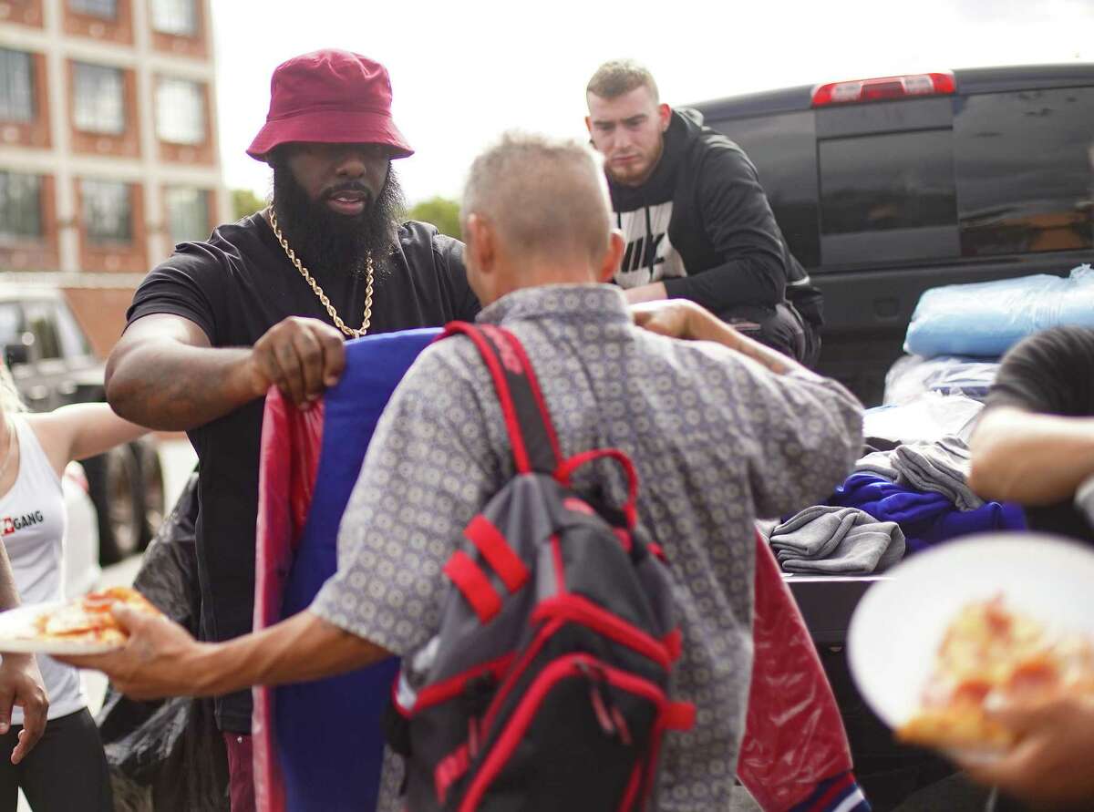 Trae tha Truth sizes up a jacket for a person in need as he and members of the Relief Gang hand out jackets and pizzas to the homeless in Houston on Friday, Dec. 3, 2021. The non-profit gave away over 150 jackets, purchase by Trae, as part of the multiple give-back events they are doing through out the holiday season.