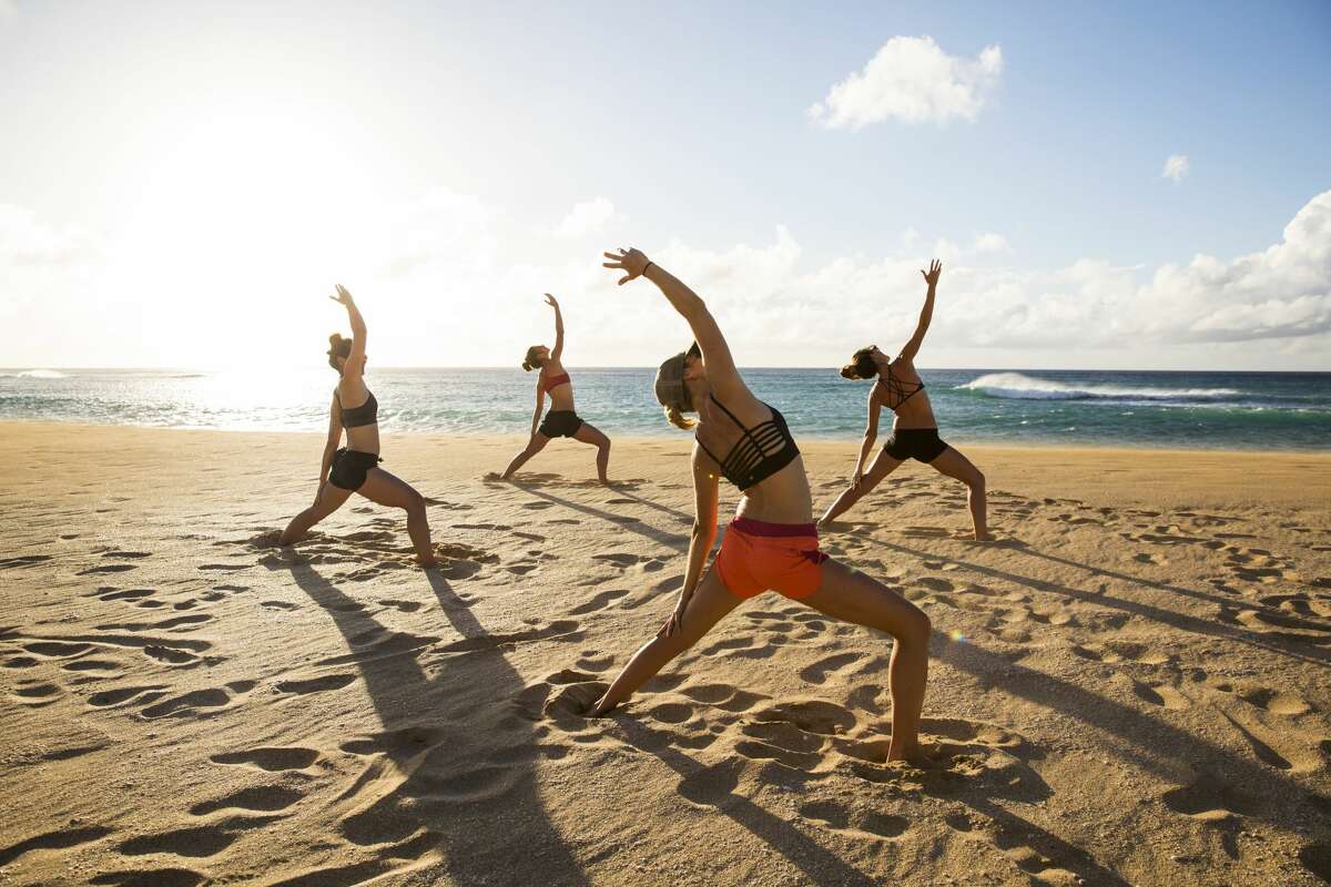 A group of friends enjoying some evening beach yoga while vacationing in Hawaii.