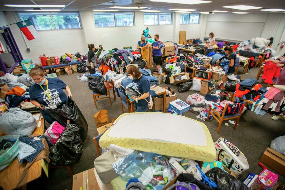 Volunteers sort through donations for eight families who lost either their entire homes or their belongings in a fire at the Shadowdale Oaks Apartments, Friday, Dec. 31, 2021, at Spring Oaks Middle School in Houston. School and community members started putting together lists of the families’ needs on Thursday after the fire, and after putting a call out on social media for donations, ended up collecting the room full of items over a two-hour period on Friday afternoon. Volunteers started sorting into eight different groups based on each family’s needs before delivering the items later on Friday.