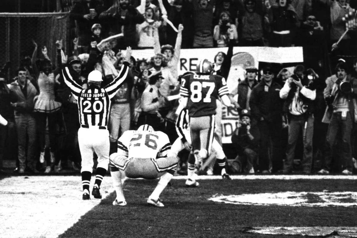 1982年，在烛台公园举行的NFC冠军赛中，49人队的外接手德怀特·克拉克(Dwight Clark)在接球后离开达拉斯自由安全球员迈克尔·唐斯(26岁)。