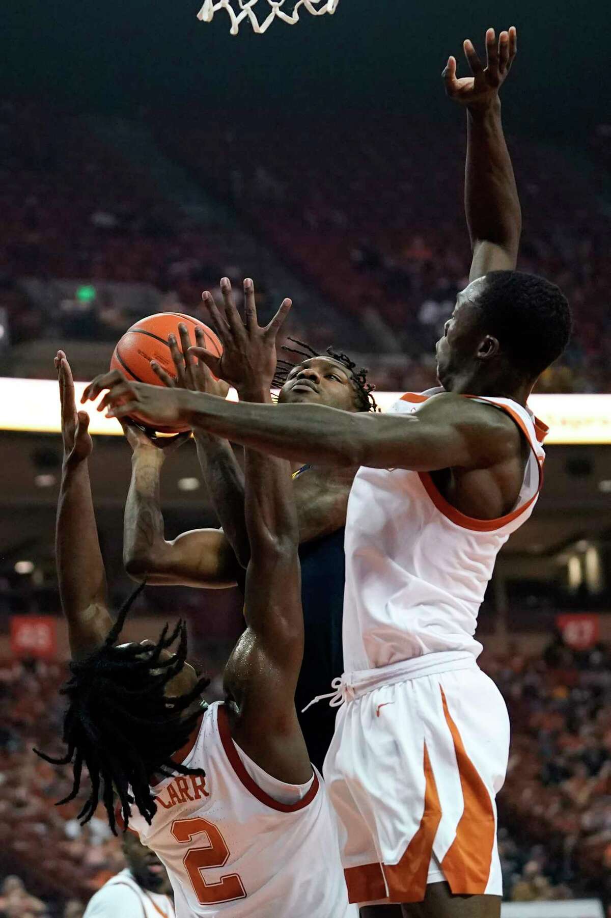 West Virginia guard Kedrian Johnson drives to the basket between Texas guard Marcus Carr (2) and guard Andrew Jones, right, during the first half of an NCAA college basketball game, Saturday, Jan. 1, 2022, in Austin, Texas. (AP Photo/Eric Gay)