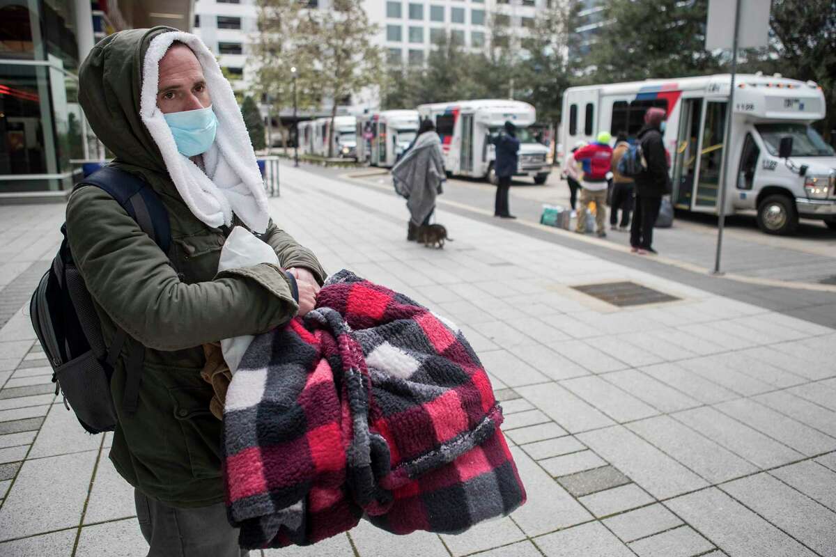 M.J. Smith stands on the sidewalk outside the George R. Brown Convention Center hoping to board a bus to take him to a warming shelter Tuesday, Feb. 16, 2021 in Houston. Temperatures stayed below freezing Tuesday, with many still without power.