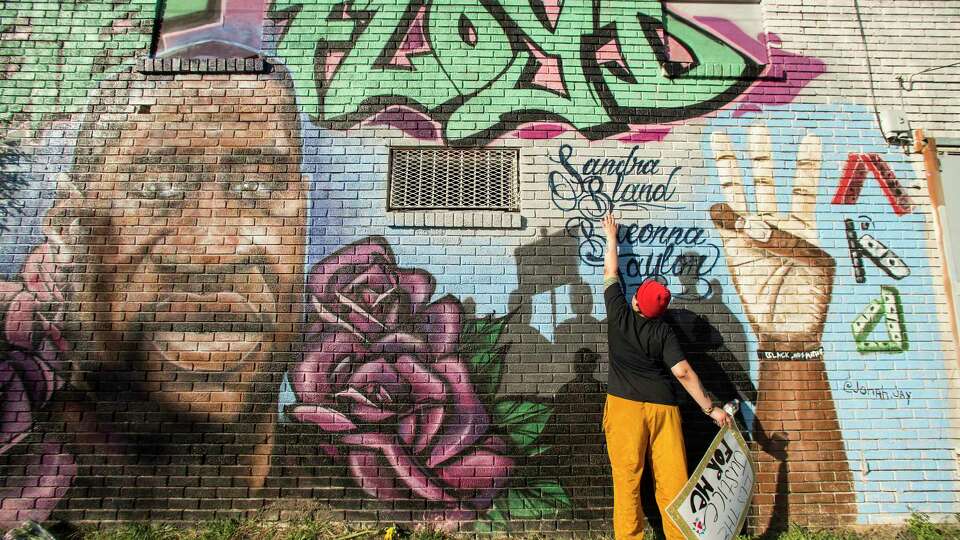 Daryel Simmons reaches up to touch the names of Sandra Bland and Breonna Taylor as she came to a George Floyd memorial mural near the intersection of Ennis and Elgin as she joins others as people react after learning of the guilty verdict on all counts in the murder trial of former Minneapolis Officer Derek Chauvin in the death of George Floyd on Tuesday, April 20, 2021, in Houston. 'It's a joyous day,' Simmons said as she celebrated the verdict.