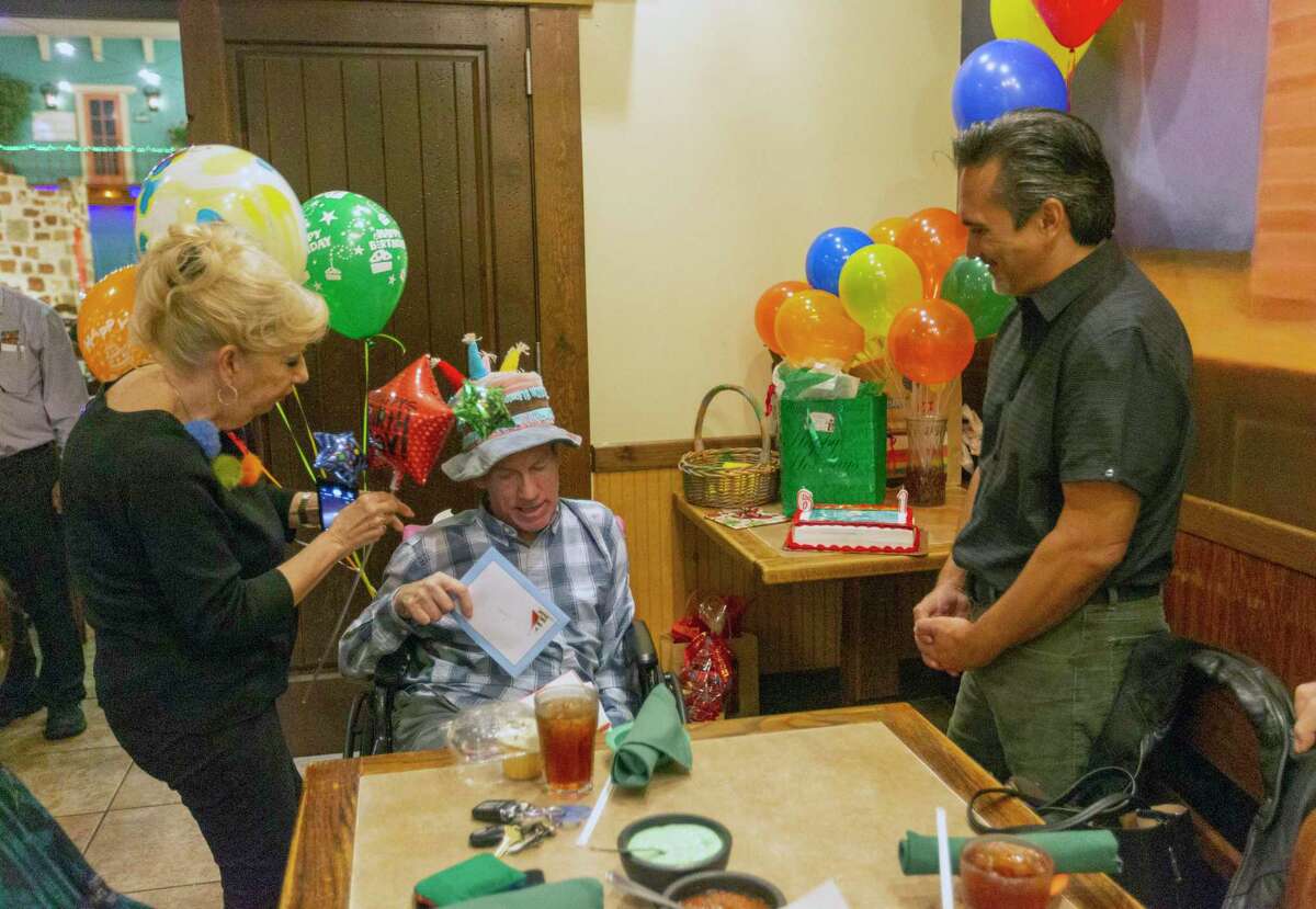 Carl Bringer, center, holds a card Dec. 28 during his birthday party at Mamacita’s Mexican Restaurant while friends Kathy Walden, left, and Paul Stahl talk to him. Bringer, once a fixture as the Santa Claus of Fredericksburg Road, was regularly seen during the holiday in his wheelchair wearing a Santa Claus outfit waving to passing motorists. Health problems have kept Bringer from that roll in recent years.