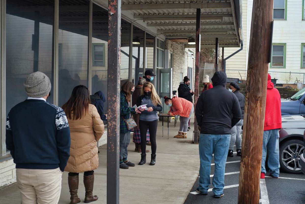 People wait in line as Albany City School District employees hand out Covid test kits outside the Harriet Gibbons Student Center on Sunday, Jan. 2, 2022, in Albany, N.Y.
