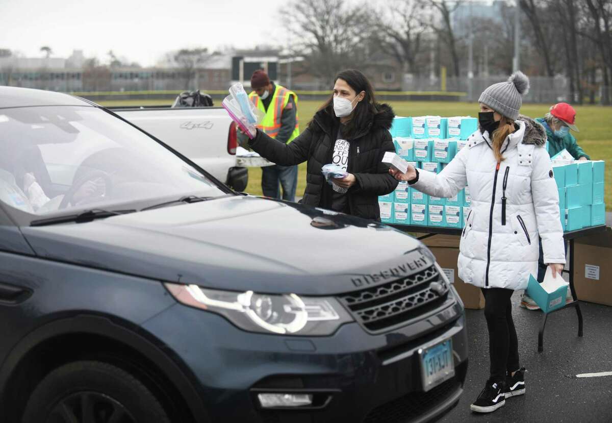 Marcella Branca, left, and Debi Coles distribute COVID test kits at Scalzi Park in Stamford, Conn. Sunday, Jan. 2, 2022. 20,000 at-home COVID test kits and masks were distributed to Stamford residents at Scalzi, Kosciuszko and Cummings Parks. Traffic near the distribution locations sat at a standstill for hours as residents queued up early to get in line to receive the test kits.