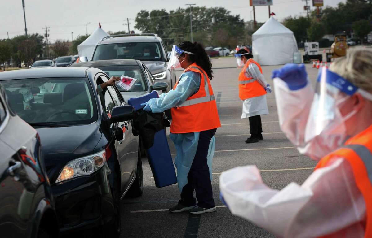 Claudia Herrera collects a COVID-19 test packet from a person after they took the test Wednesday, Dec. 29, 2021, at Delmar Stadium in Houston. The Houston Health Department and Curative opened the drive-thru mega-site that morning.