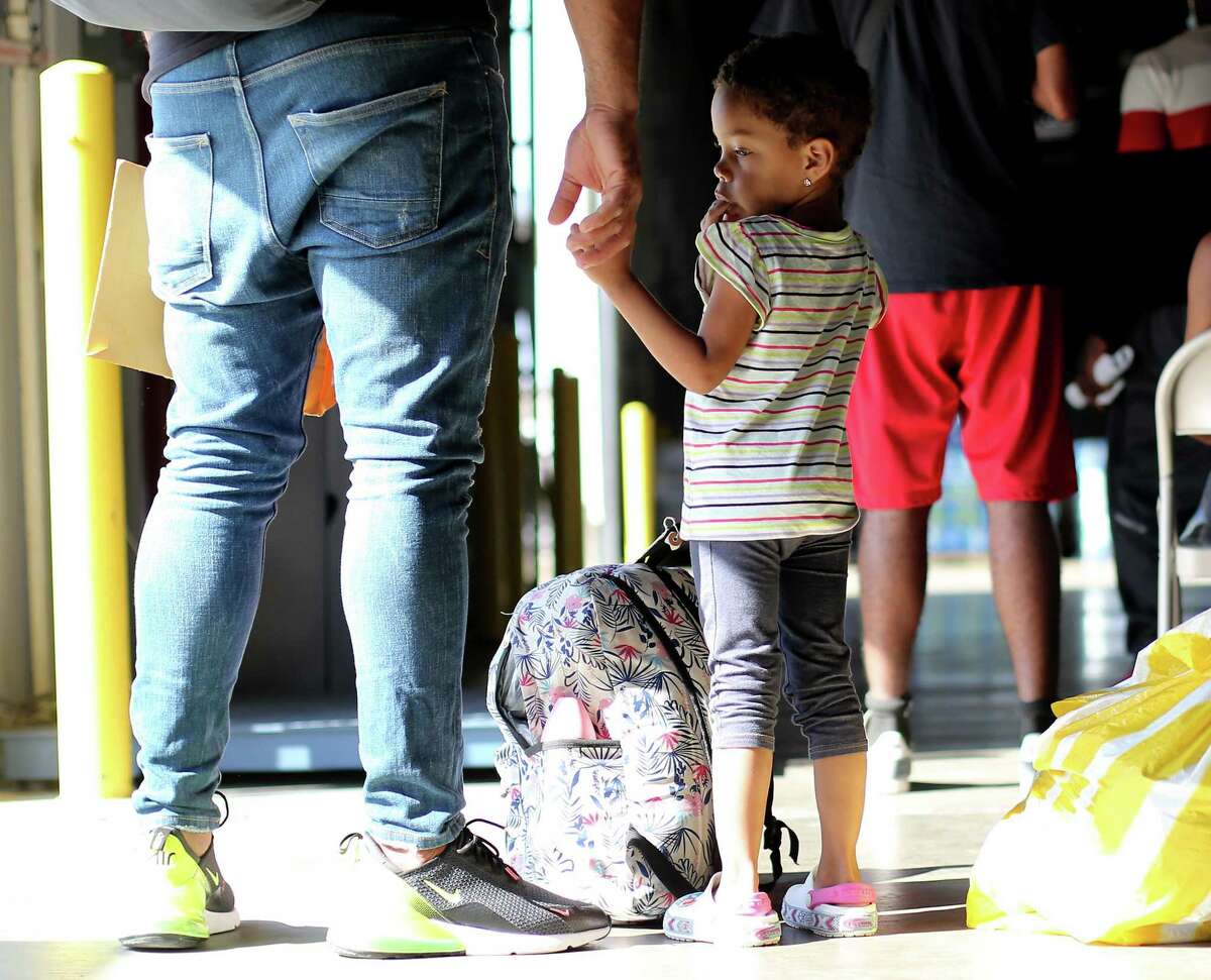 Nicola Peña, 2, of Dominican Republic, holds her dad's hand Sept. 21 at a shelter in Houston.