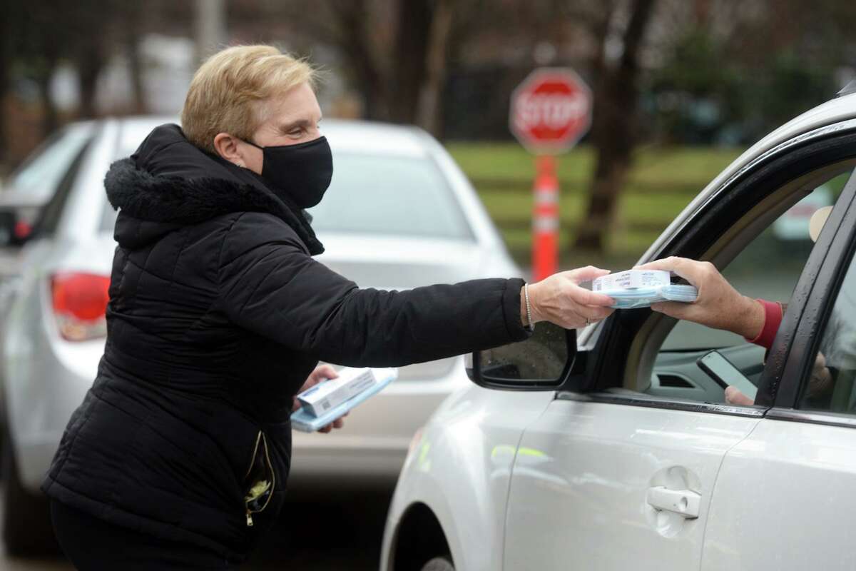 First Selectman Vicki Tesoro hands out COVID-19 home test kits during a during drive-thru pickup at Unity Park, in Trumbull, Conn. Jan. 2, 2022.