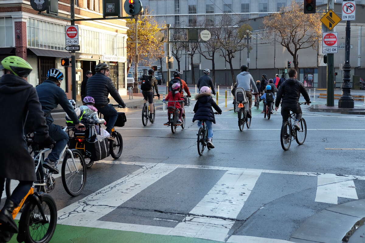 Families ride through San Francisco's Golden Gate Park as part of a "bike bus" in December 2021.