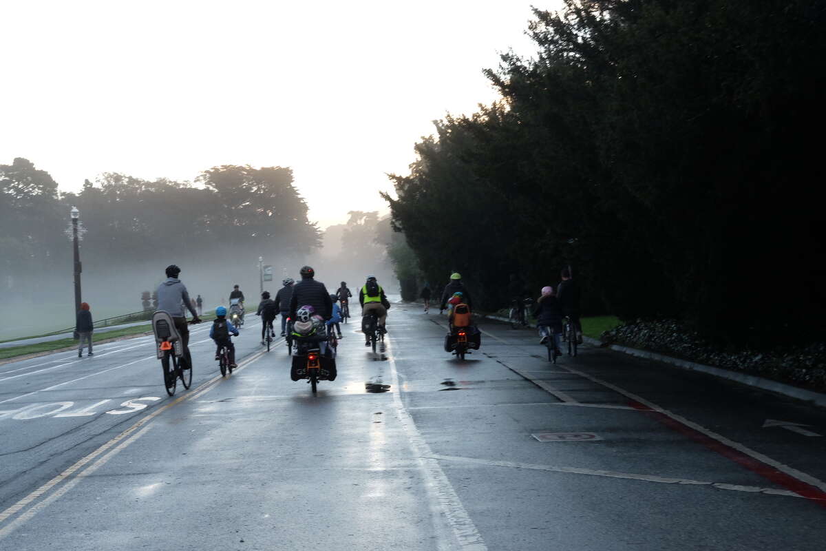 Families ride through San Francisco's Golden Gate Park as part of a "bike bus" in December 2021.