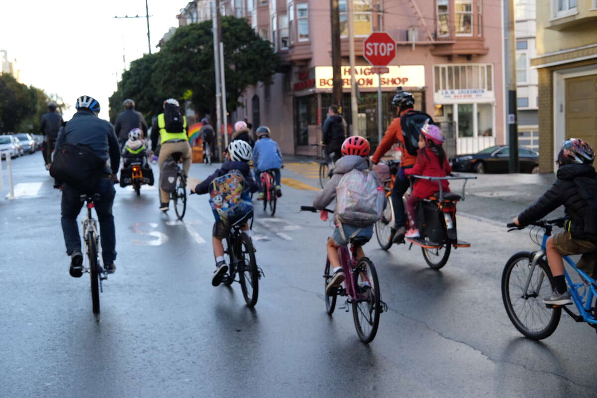 Families ride through San Francisco's Golden Gate Park as part of a "bike bus" in December 2021.