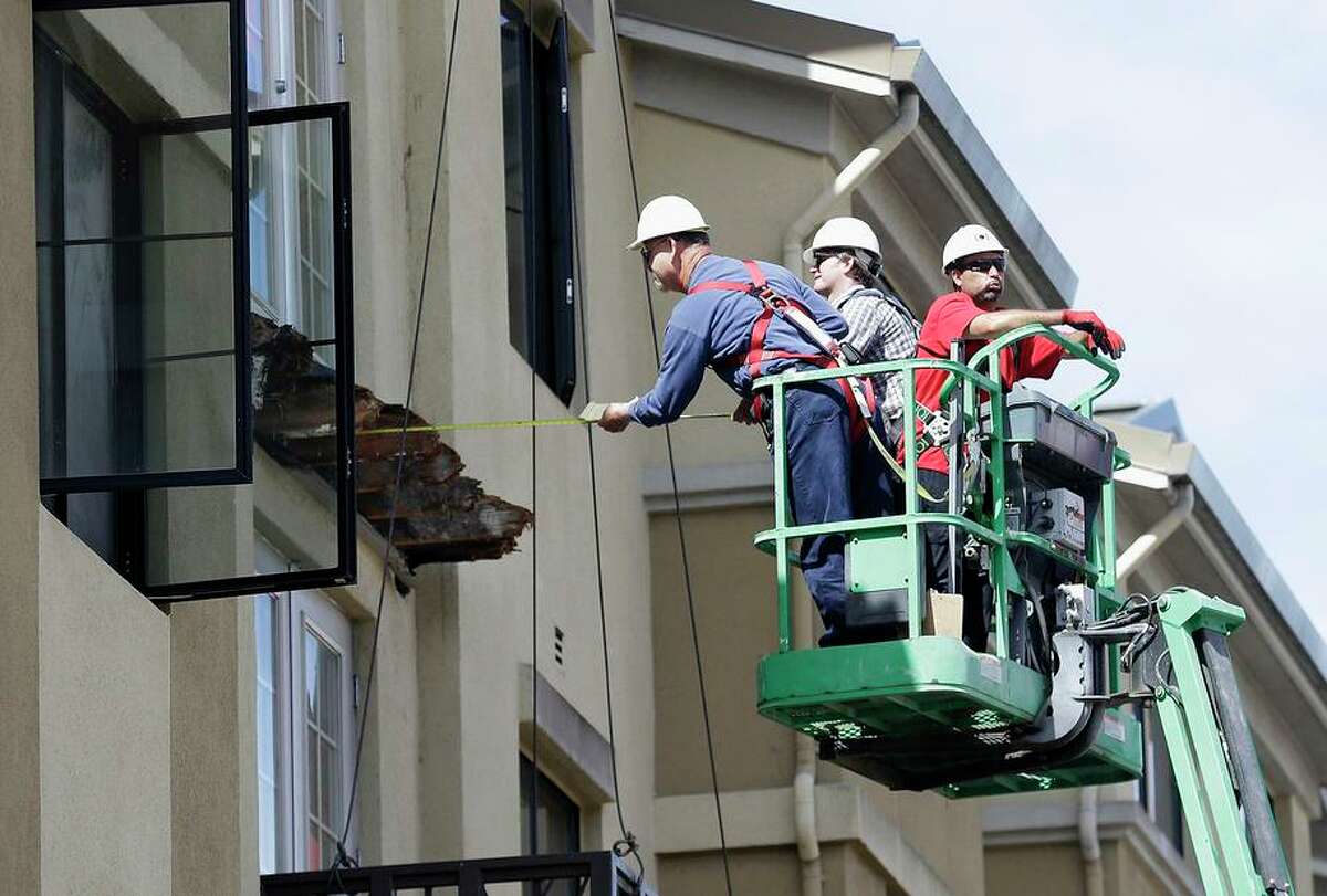 A worker measures the remaining wood from the balcony of a Berkeley apartment building that collapsed in 2015, killing six.