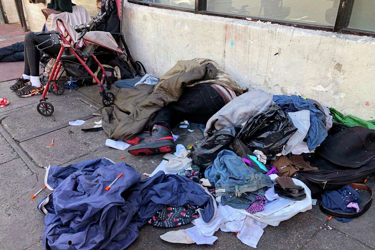 FILE - People sleep near discarded clothing and used needles on a street in the Tenderloin neighborhood in San Francisco, on July 25, 2019. (AP Photo/Janie Har, File)